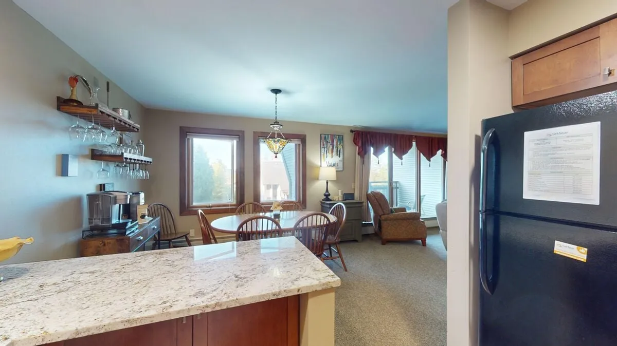 This image highlights a dining area with a granite countertop and a table set near windows that flood the space with natural light. The seating area looks out toward the outdoors, hinting at the beautiful surroundings that can be enjoyed from within the home. The warm and inviting atmosphere suggests a welcoming space for gatherings after fall adventures.