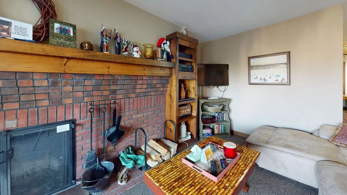 A warm, inviting living area featuring a brick fireplace with a wooden mantel, decorative accents, a plush couch, and a coffee table. The setting is ideal for relaxing after crisp autumn hikes or festival outings, echoing the retreat-like atmosphere described in the section.