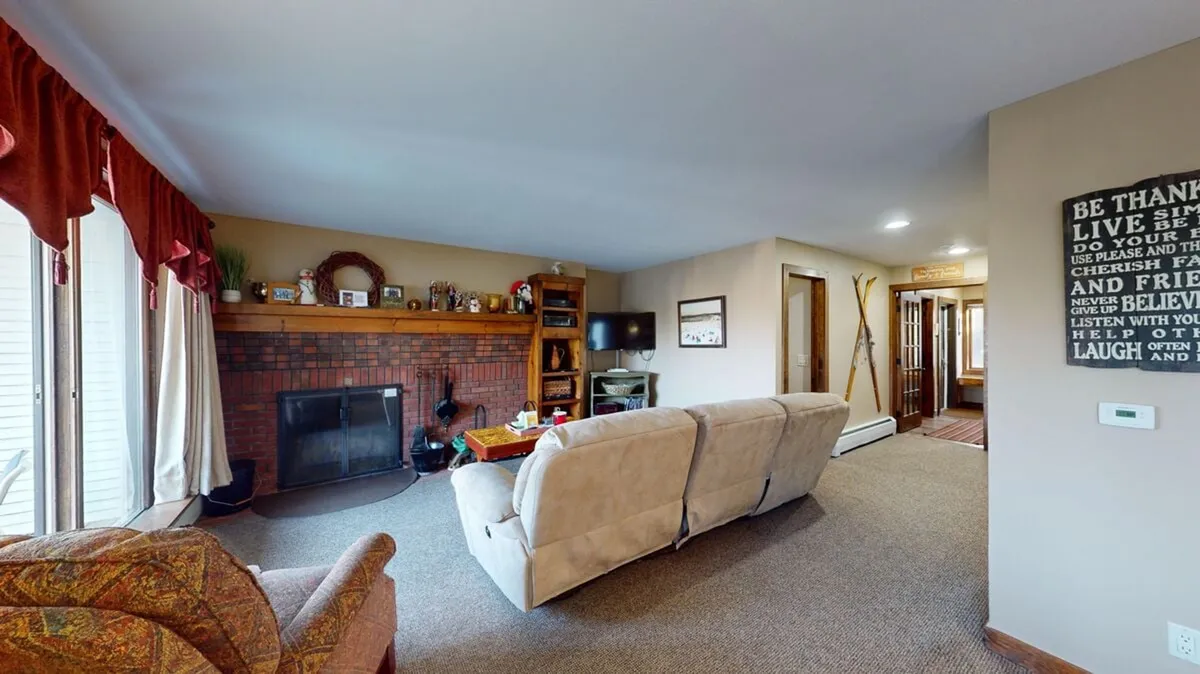 A spacious, comfortable living room anchored by a wood-burning fireplace, surrounded by plush sofas and stylish decor. The room invites relaxation, conversation, and cozy evenings spent together.